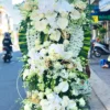 Vòng hoa tang trắng Tưởng Niệm CB028 với hoa cúc, ly và lan, biểu tượng của lòng kính trọng và tiếc thương.
