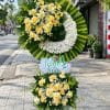Trọn Vẹn CB029: vòng hoa chia buồn vòng hoa trắng lệch, lá xanh và cụm hoa dưới