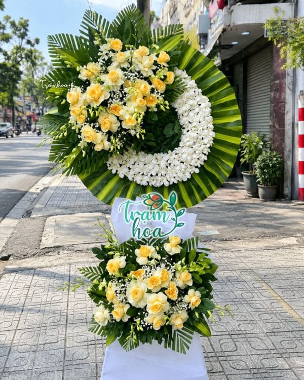 Trọn Vẹn CB029: vòng hoa chia buồn vòng hoa trắng lệch, lá xanh và cụm hoa dưới