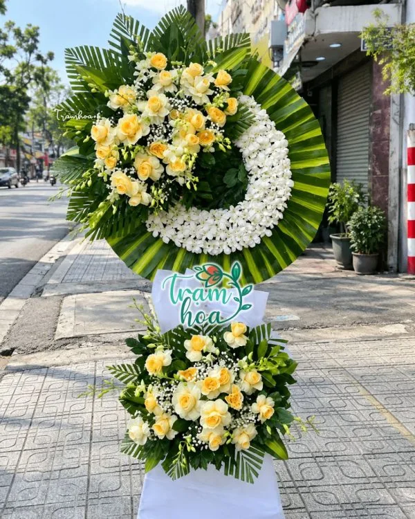 Trọn Vẹn CB029: vòng hoa chia buồn vòng hoa trắng lệch, lá xanh và cụm hoa dưới