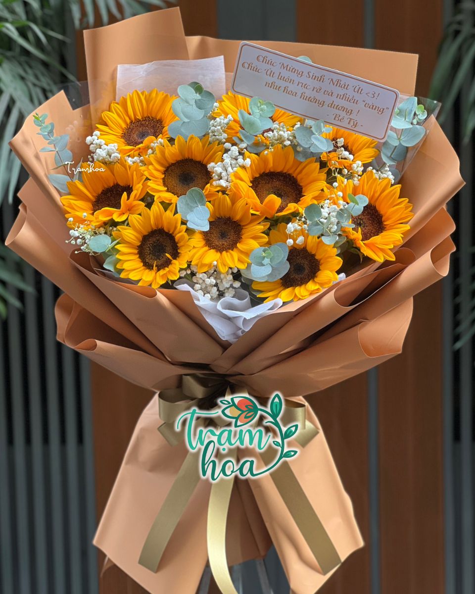 Bó hoa hướng dương rực rỡ: Kết hợp với lá bạc và giấy gói sang trọng, món quà của sự vui vẻ, lạc quan.